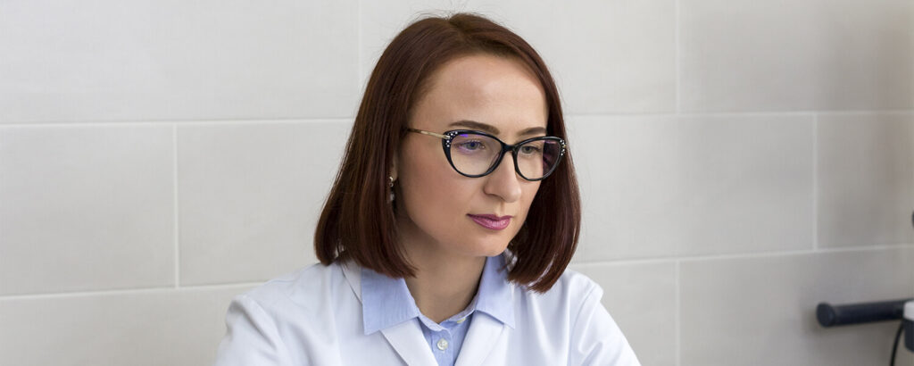 Врач — женский уролог в белом халате на рабочем месте в клинике